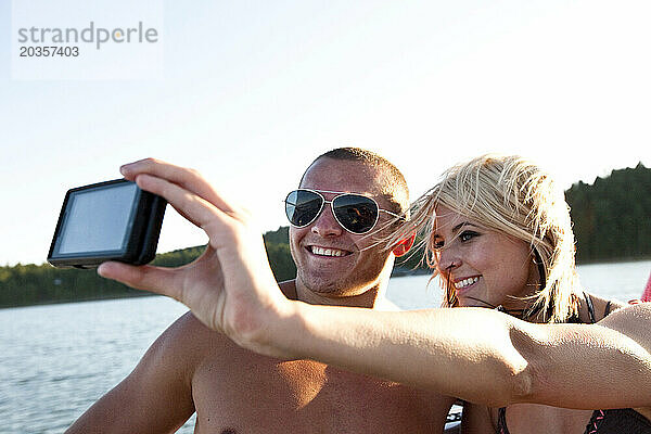 Zwei junge  glückliche Erwachsene lächeln  während sie auf einem Wakeboard-Boot in Idaho ein Foto machen.