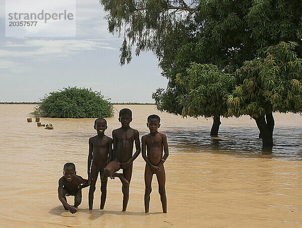 Vier nackte afrikanische Songhai-Kinder stehen am Rande eines großen schmutzigen Sees  Gossi  Mali  Westafrika