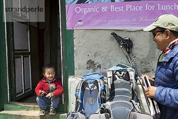 Wanderer unterhält sich mit einem nepalesischen Jungen im Teehaus  wo Wanderer sich ausruhen und essen können  Pangboche  Khumbu  Nepal