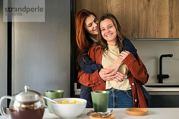 Lesbisches Paar  das sich in der Küche verliebt umarmt.