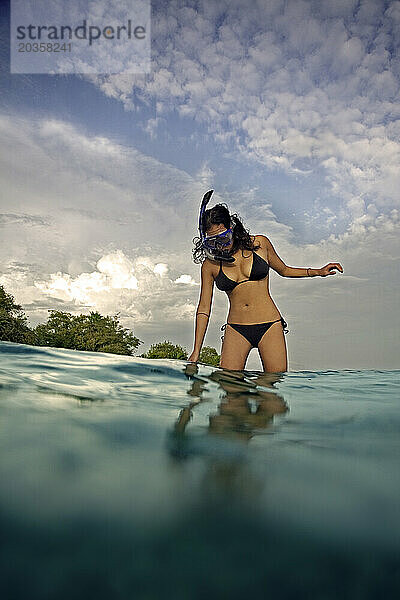 Eine junge Frau trägt einen Schnorchel und spaziert im Mittelmeer.