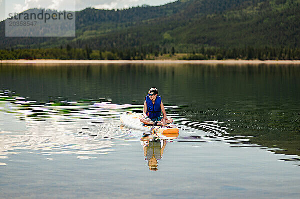 Junge auf Paddleboard im ruhigen Bergsee