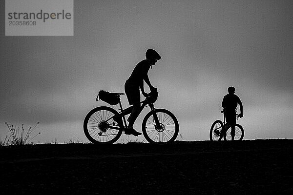 Zwei Mountainbiker zeichnen sich als Silhouette gegen den Himmel ab  Ruanda