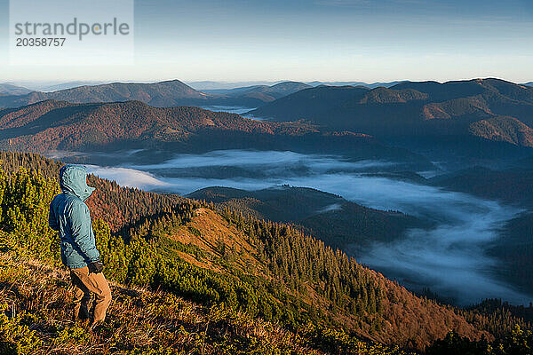 Wanderer allein mit Blick auf die Aussicht vom Berggipfel  erstes Morgenlicht