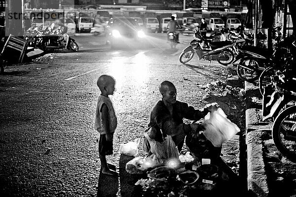 Mutter durchwühlt Müll auf der Straße  während ihr Sohn zusieht  Hanoi  Vietnam.