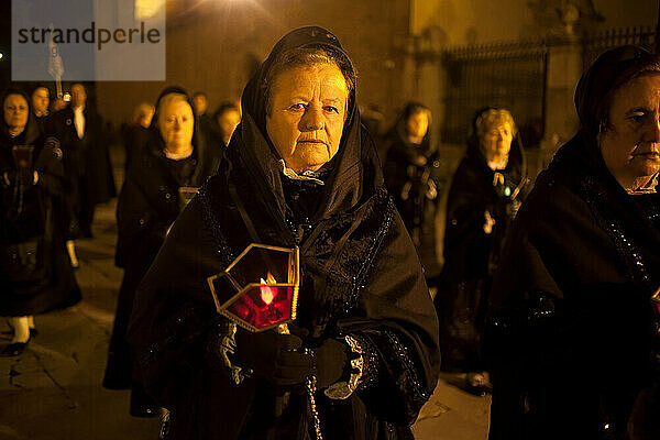 Eine Frau  die eine Mantilla anzieht  hält eine Kerze während einer Prozession der Karwoche in Astorga  Kastilien und León  Spanien.