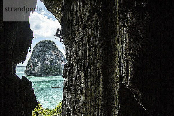 Mann klettert am Rand einer Höhle  Phra Nang Beach  Krabi  Thailand