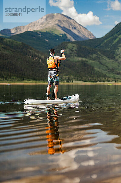 Paddleboarder mit Bergblick genießt die Ruhe des Sees