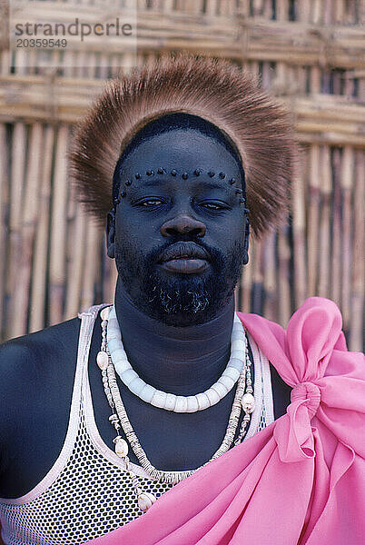 Der göttliche König trägt einen Löwenkopfschmuck und Narben auf der Stirn  die typisch für seinen Stamm Sudan sind.