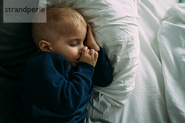 Nahaufnahme eines friedlich schlafenden Kleinkindes  das am Daumen lutscht