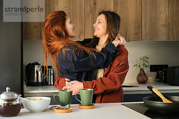 Lesbisches glückliches Paar  das sich in der Küche verliebt umarmt.