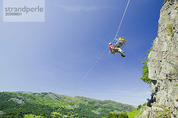 Mitglieder des Langdael Ambleside Mountain Rescue Teams führen im Rahmen des Trainings eine Trage in Langdale einen Felsvorsprung hinab.