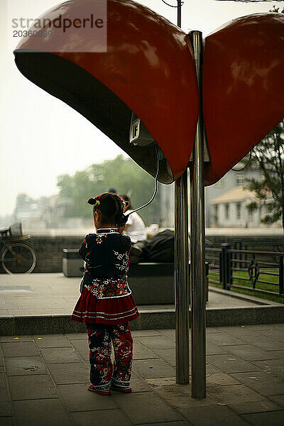 Ein Mädchen steht unter einer Telefonzelle in Peking  China.
