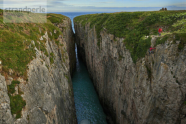 Fernsichtaufnahme von Menschen  die eine Küstenklippe hinaufklettern  Pembroke  Wales  Großbritannien