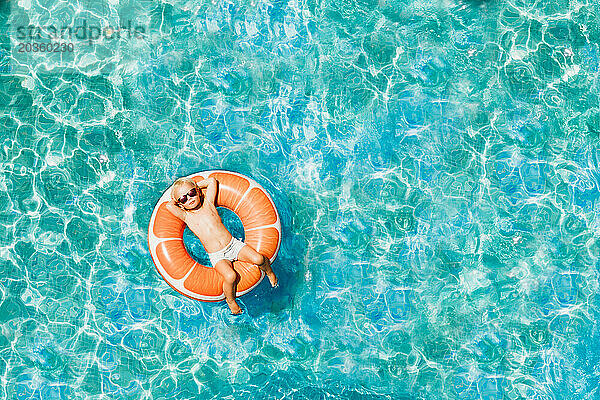 Junge hat Spaß im Familienurlaub und ruht sich im Pool mit Donut-Ring aus