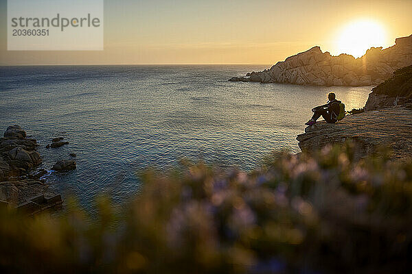 Blick auf eine Frau  die auf einer Klippe am Meer sitzt  Sardinien  Italien