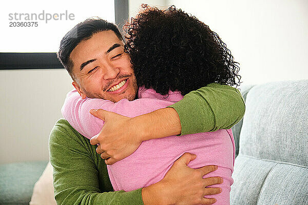 Chinesischer Mann umarmt seine dominikanische Freundin zu Hause.