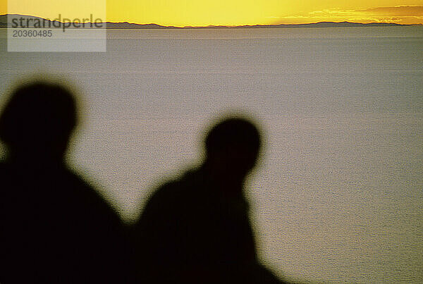 Ein Paar blickt auf den Sonnenuntergang in der Nähe eines Sees in Bolivien.