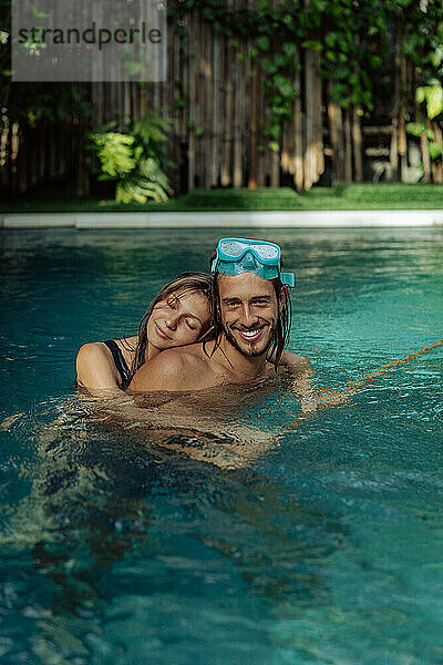 Glückliches junges verliebtes Paar im Pool im Urlaub in den Tropen.