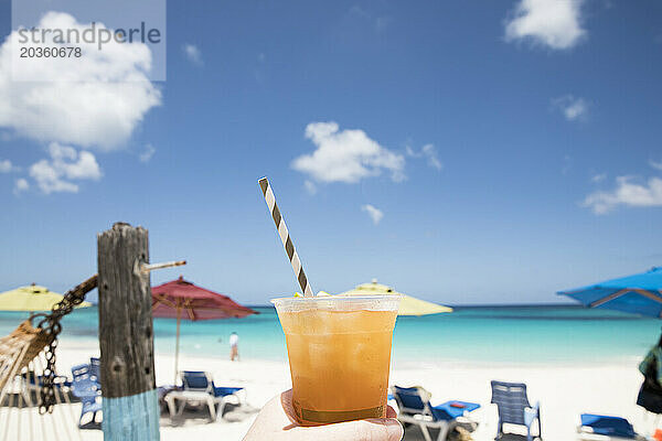 Tropisches Getränk mit gestreiftem Strohhalm vor dem blauen Himmel der Karibik