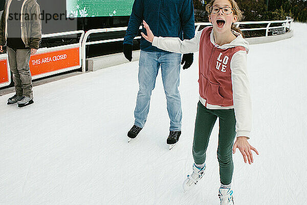 Zwei Mädchen laufen im Winter mit ihrem Vater Schlittschuhe auf dem Eisweg