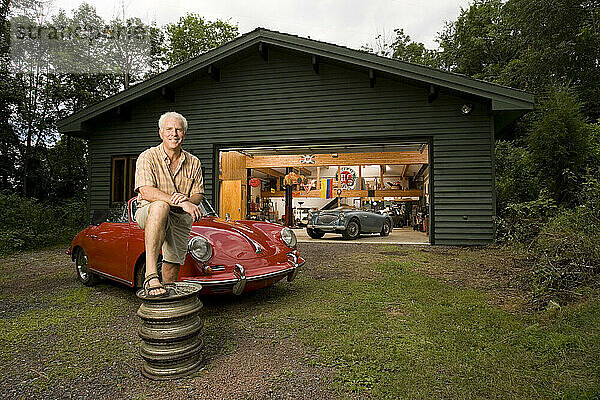 Ein Mann posiert mit seiner Sammlung antiker Sportwagen vor seiner Garage in Pennsylvania für ein Porträt.