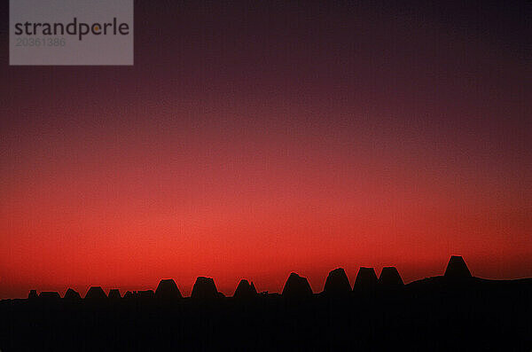 Sonnenuntergang hinter einer Reihe silhouettierter alter Pyramiden im Nordsudan.