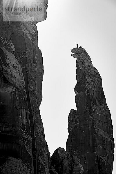 Tiefwinkelaufnahme eines Bergsteigers  der auf dem Gipfel einer Klippe vor dem Himmel steht