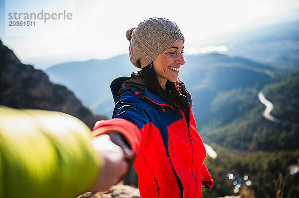 Bergsteigerpaar lächelt und hält sich an den Händen.