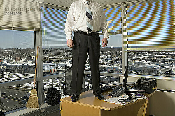 Ein Mann steht auf seinem Schreibtisch in einer Firmenzentrale.