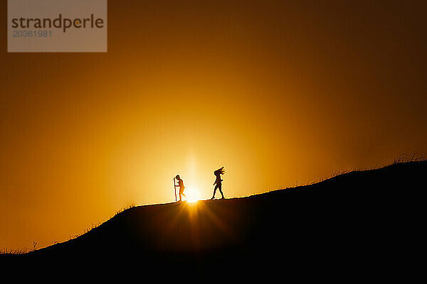 Zwei Kinder gehen im Sonnenuntergang den Hügel hinunter