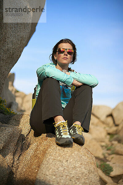 Blick auf eine junge Frau  die auf einem Stein sitzt  Sardinien  Italien