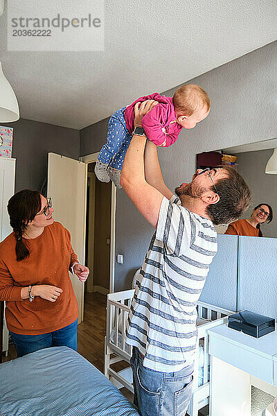 Glückliche Eltern  die zu Hause mit ihrem 6 Monate alten Mädchen spielen.