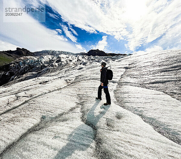 Mann wandert auf Gletscher am Berg mit Sonnenschein und Eisspitze