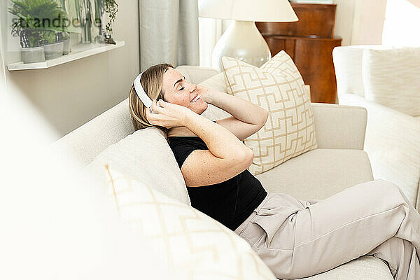 Frau entspannt sich bei Musik auf der gemütlichen Couch