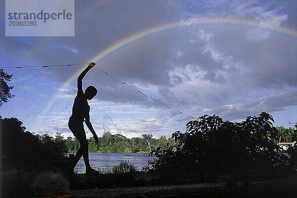 Silhouette eines kleinen Jungen mit einem Fischernetz  Suriname  Südamerika.