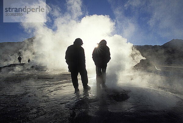 Zwei Personen stehen in der Nähe der geothermischen Tatia-Geysire.