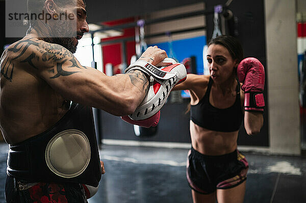 Boxerin beim Sparring mit Personal Trainer im Fitnessstudio