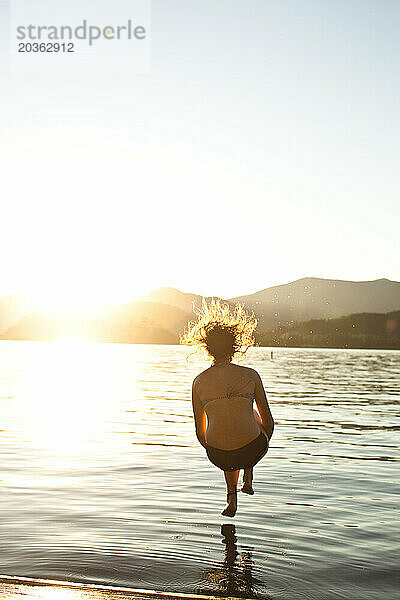 Eine glückliche junge Frau schießt bei Sonnenuntergang in Idaho Kugeln in einen See.