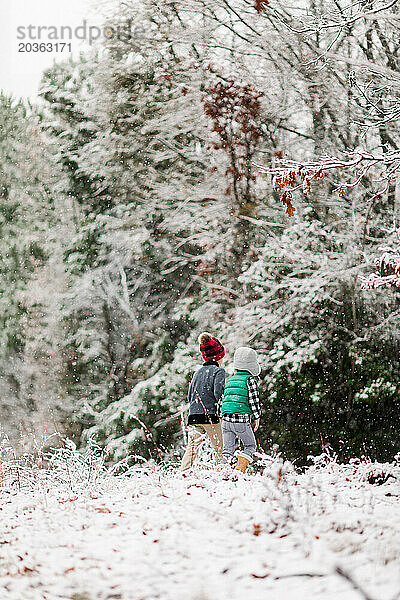 Zwei kleine Jungen erkunden den Wald im Schnee