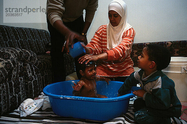 Mohammed El-Bishi  seine Frau Nibeal und seine Söhne Saud  3  und Nour Al-deen  8 Monate in ihrem Haus in Amman  Jordanien. Nibeal fügt heißes Wasser aus einem auf dem Herd erhitzten Topf hinzu  um das Gericht zuzubereiten