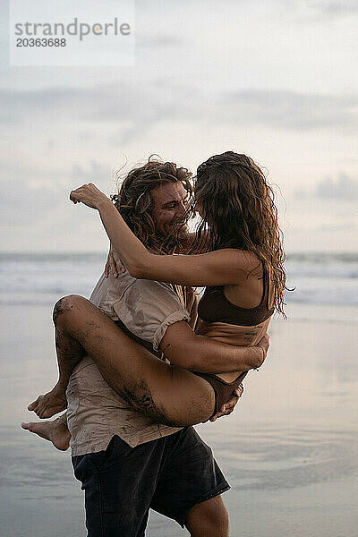 Junges fröhliches  glückliches verliebtes Paar  das am Strand herumalbert.