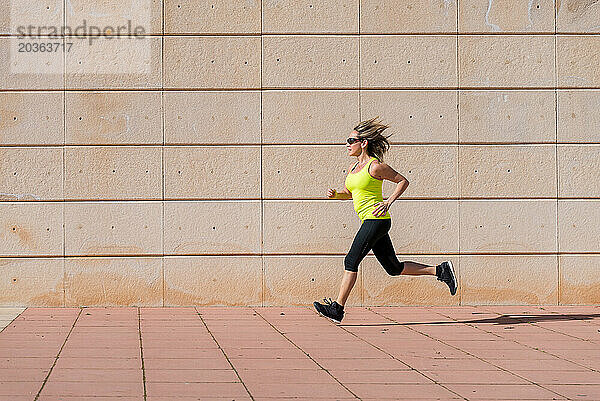 Erwachsene Frau läuft beim Training entlang einer weißen Musterwand