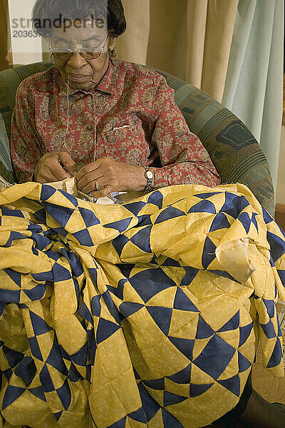An elderly woman quilting.
