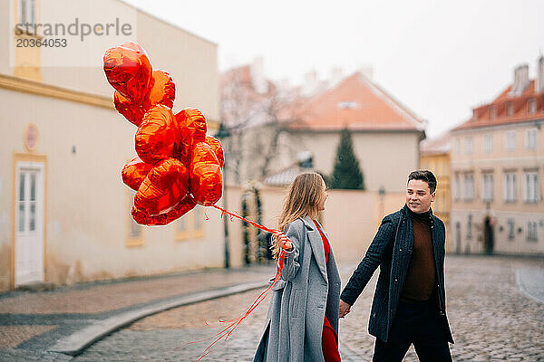 Junges Paar geht mit Luftballons im Herzen durch Prag