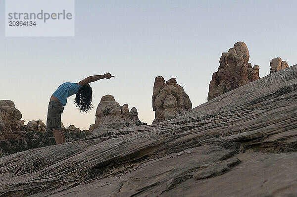 Eine Frau praktiziert Yoga zwischen Felsformationen.