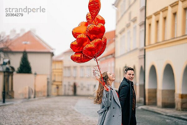 Junges Paar geht mit Luftballons im Herzen durch Prag