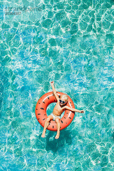 Kleines Kind hat Spaß im Wassermelonen-Floatie mit Drohnenblick am Pool