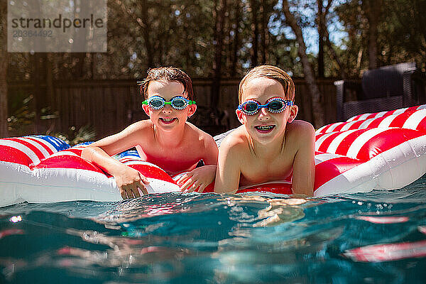 Fröhliche Kinder mit ausgefallenen Schwimmbrillen genießen die Zeit im Pool an einem sonnigen Tag