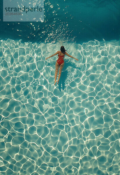 Frau entspannt beim Schwimmen im Pool im Urlaub